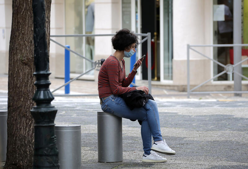 A woman, wearing a protective face mask, looks at her mobile phone in Nice following the outbreak of the coronavirus disease (COVID-19) in France, May 27, 2020. REUTERS/Eric Gaillard