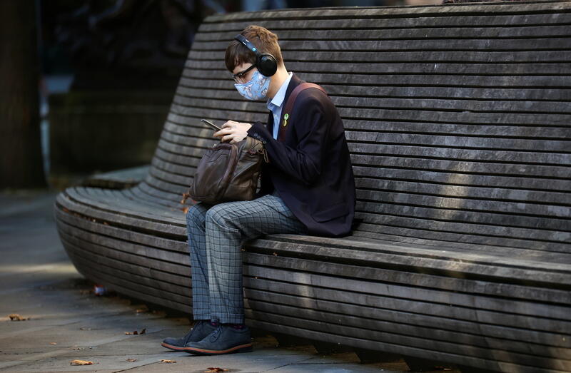 A person wearing a protective mask looks at a mobile phone in Manchester. 