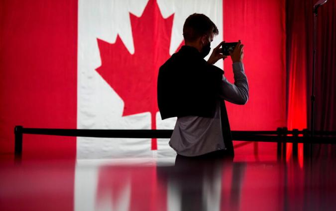 A person in front of a Canadian flag holds a cell phone ahead of the Liberal election night party, in Montreal, Quebec, Canada, September 20, 2021. REUTERS/Carlos Osorio