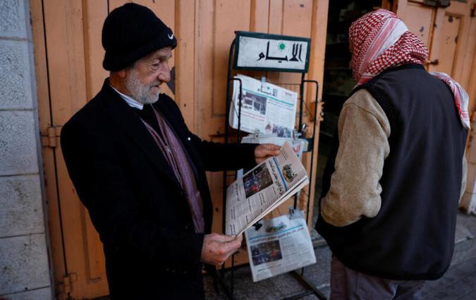 A Palestinian man reads a newspaper near closed shops, during a strike as a protest against the killing of senior Hamas official, Saleh al-Arouri, in Hebron in the Israeli-occupied West Bank January 3, 2024. REUTERS/Mussa Qawasma