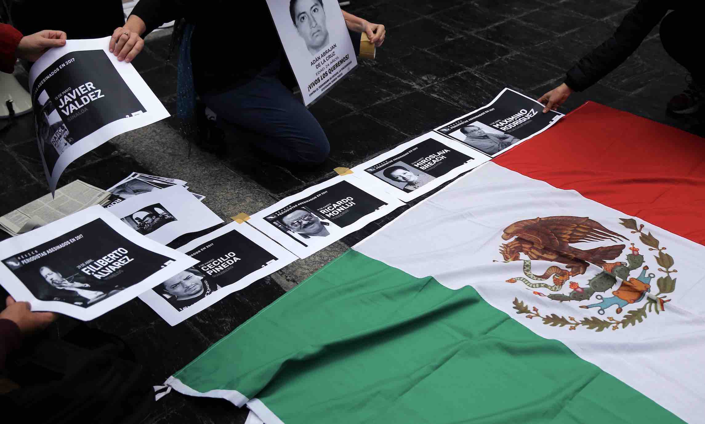 People place photos of murdered journalists next to the national Mexican flag in Buenos Aires. Reuters/Marcos Brindicci