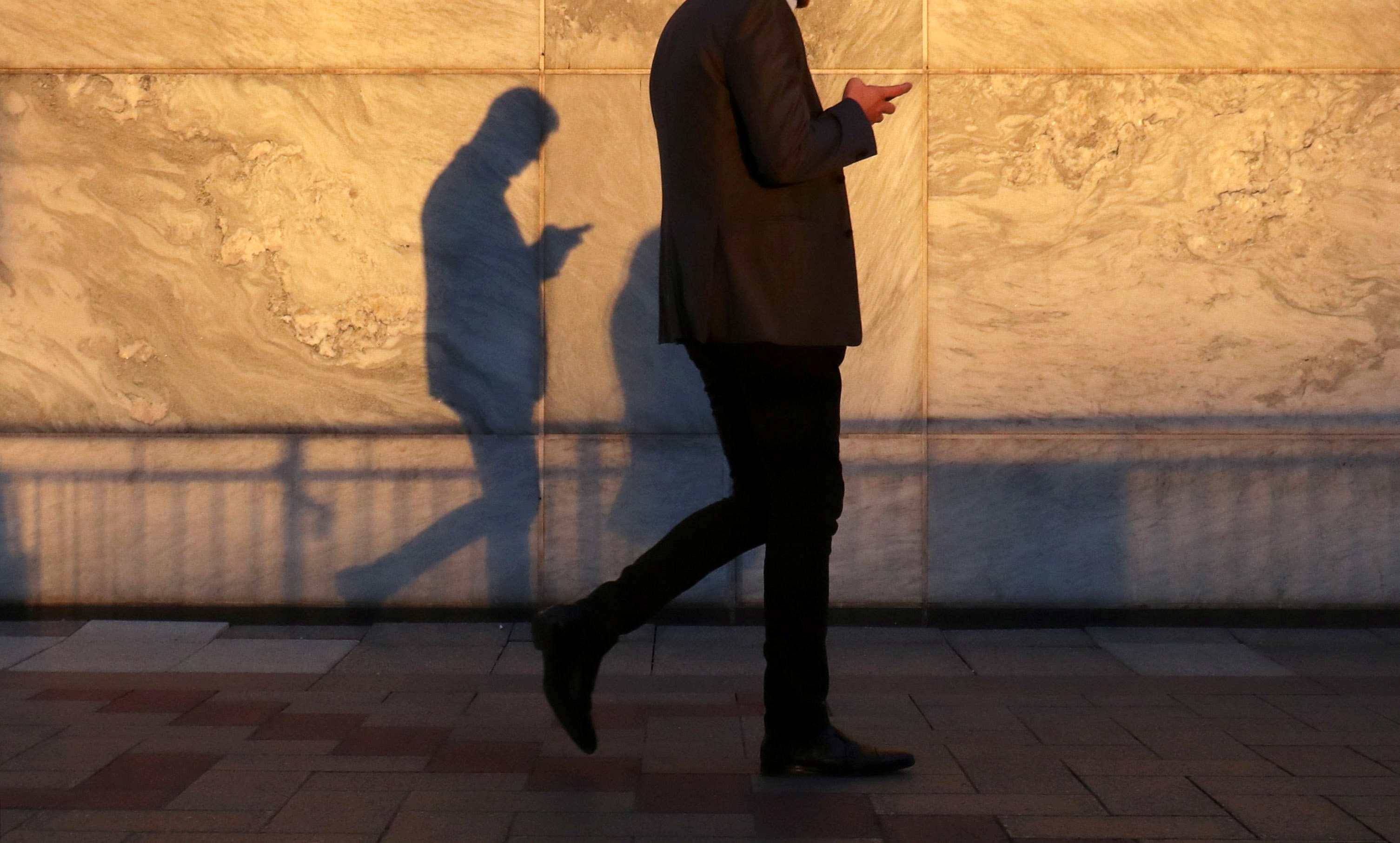 An unidentified man using a smart phone walks through London's Canary Wharf financial district in the evening light in London, Britain, September 28, 2018. REUTERS/Russell Boyce