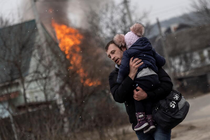 A man and a child escape from the town of Irpin, after heavy shelling on the only escape route used by locals, while Russian troops advance towards the capital of Kyiv, in Irpin, near Kyiv, Ukraine March 6, 2022. REUTERS/Carlos Barria
