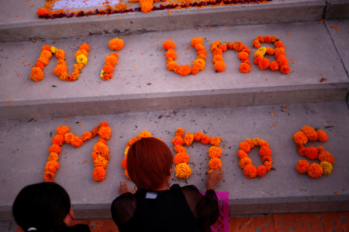 A woman places flowers on an altar in memory of femicide victims before the Day of the Dead in Ciudad Juarez, Mexico, October 31, 2021. The letters read "Not one less". REUTERS/Jose Luis Gonzalez