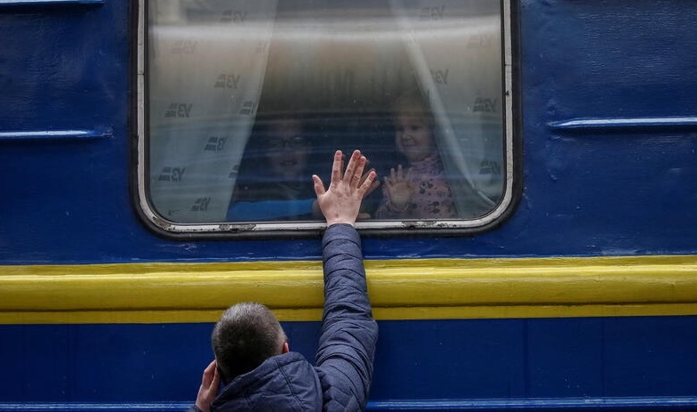 Children look out from an evacuation train from Kyiv to Lviv as they say goodbye to their father at Kyiv central train station in central Kyiv, Ukraine March 3, 2022. REUTERS/Gleb Garanich