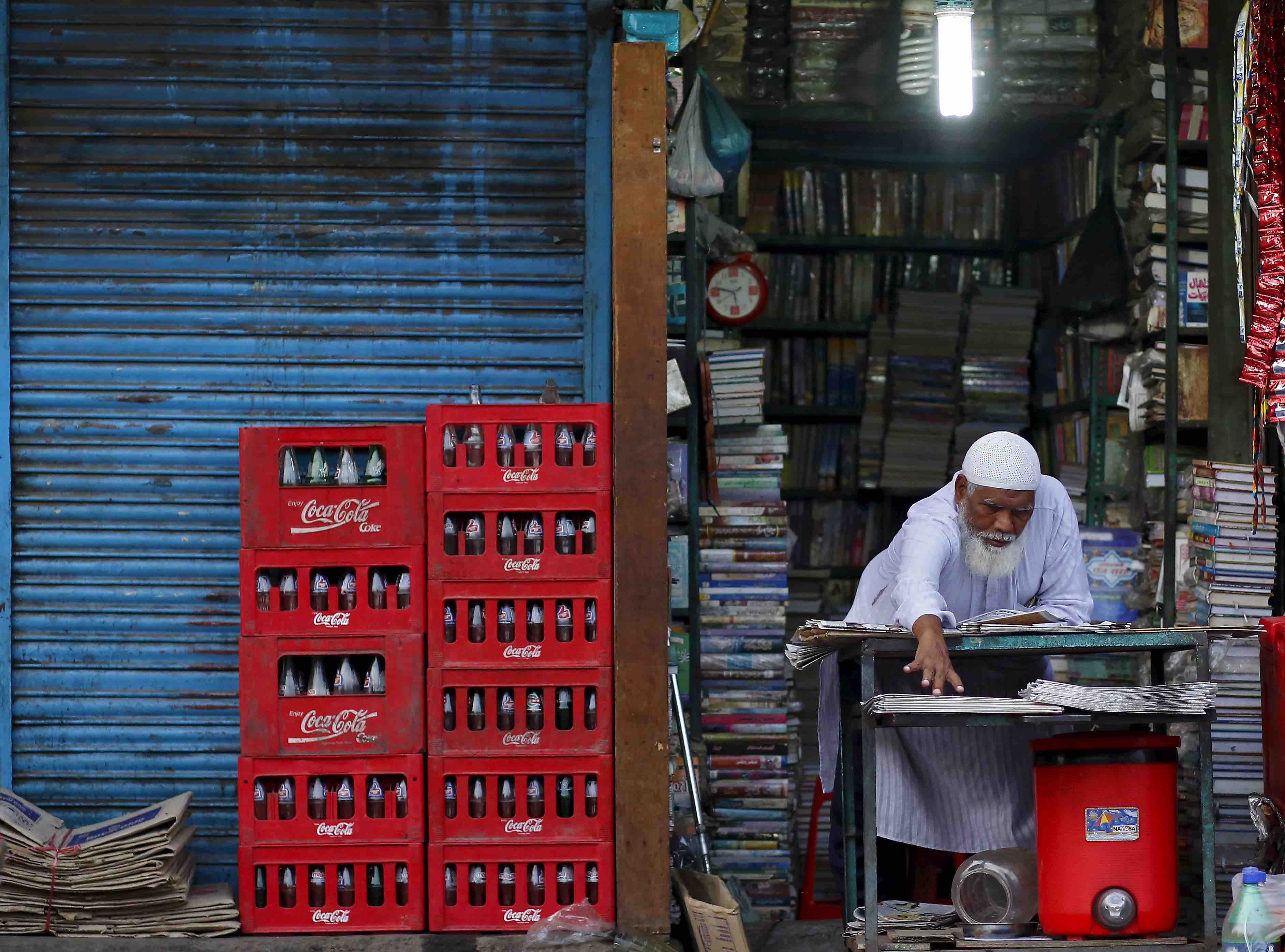 A shopkeeper extends his hand as he arranges newspapers for sale at his shop during early morning in the old quarters of Delhi, India, July 2, 2015. REUTERS/Anindito Mukherjee