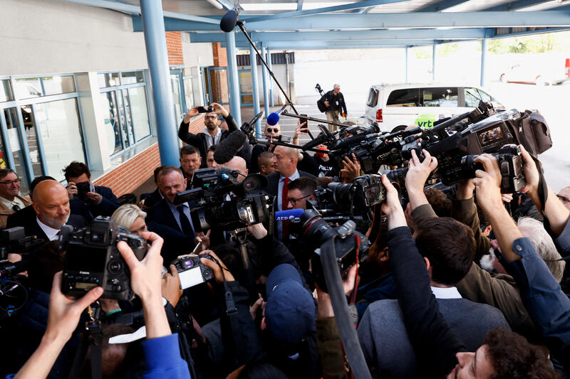 Marine Le Pen is surrounded by journalists during the 2022 presidential election campaign in France.