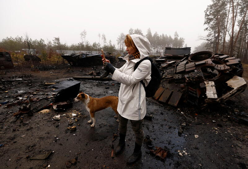 Iryna Vereshchagina films with her phone Russian destroyed tanks beside Kyiv. REUTERS/Zohra Bensemra