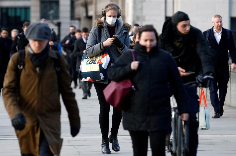 A woman wearing a face mask uses her phone on London Bridge in March 2020. REUTERS/Henry Nicholls