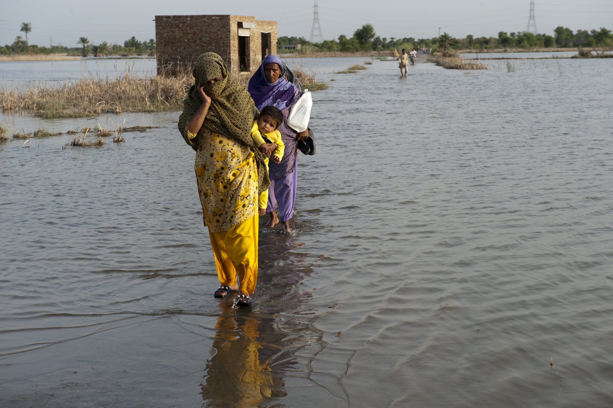 A family crosses the flooded streets of Pakistan. Credit: ADB