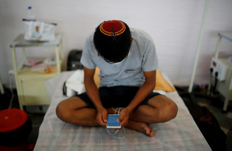 An Indian checks his mobile phone at a COVID-19 care facility in New Delhi. REUTERS/Adnan Abidi 