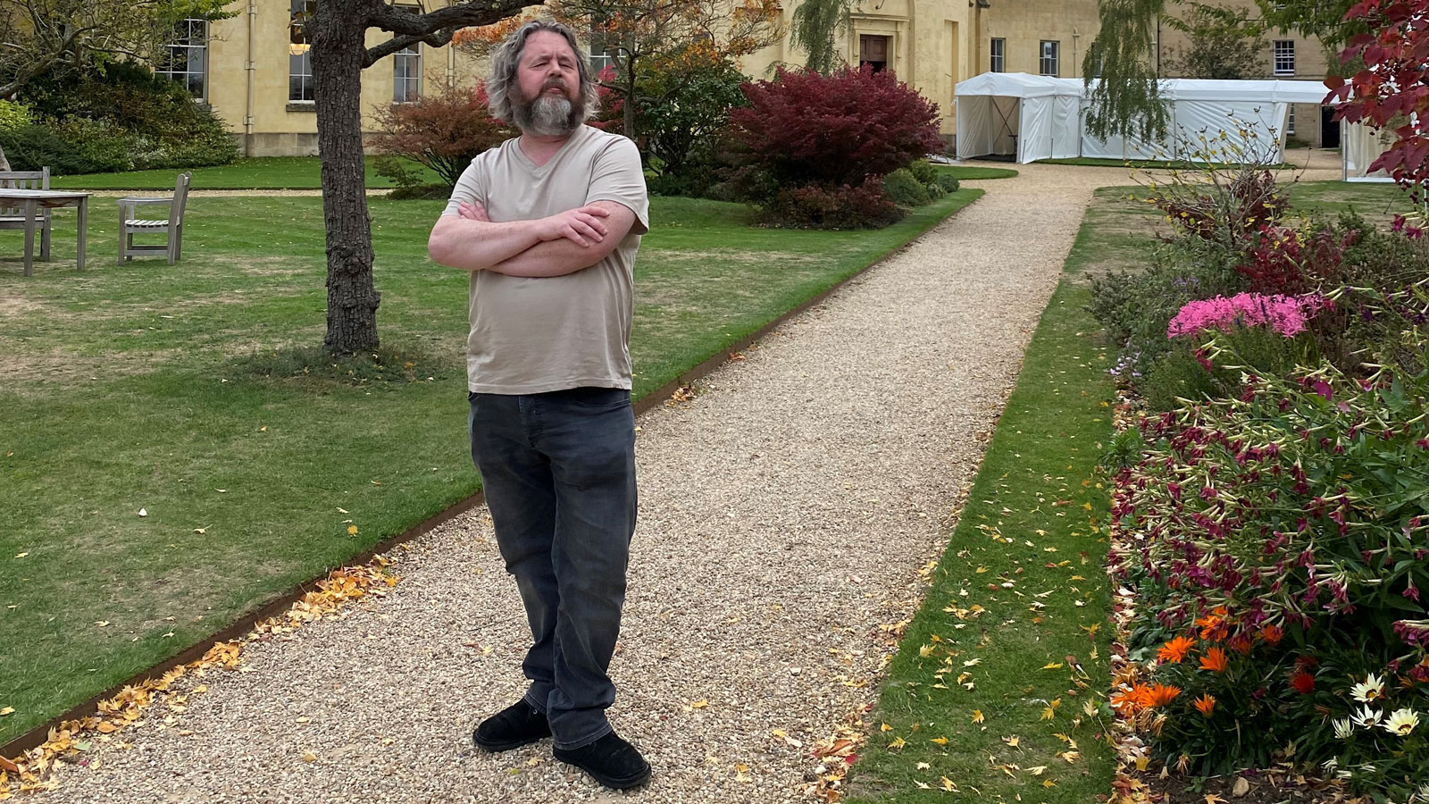 BBC journalist Johny Cassidy stands, arms crossed, on a pathway inside Green Templeton College at Oxford University.