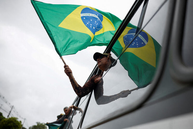 A man holds a Brazilian flag from the window of a bus as he is detained after a camp set by supporters of Brazil's former President Jair Bolsonaro was dismounted in Brasilia, Brazil, January 9, 2023. REUTERS/Amanda Perobelli 