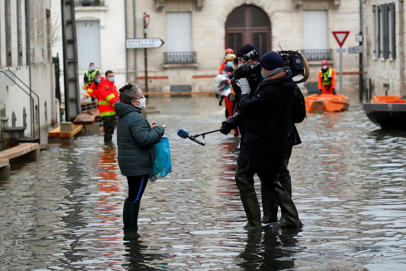 Journalists conduct interviews after the Charente River in Saintes, France overflowed.
