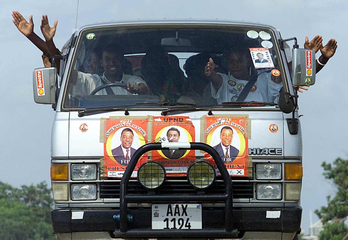 A Zambian minibus taxi carrying people who are waving enthusiastically