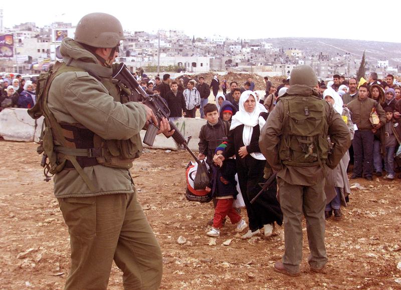 Two soldiers at a Ramallah checkpoint in 2002. A long queue has formed. 