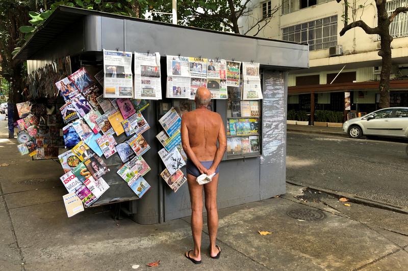 An elderly man reads the morning newspapers at a stand in Ipanema beach in Rio de Janeiro, Brazil July 24, 2019. REUTERS/Jorge Silv
