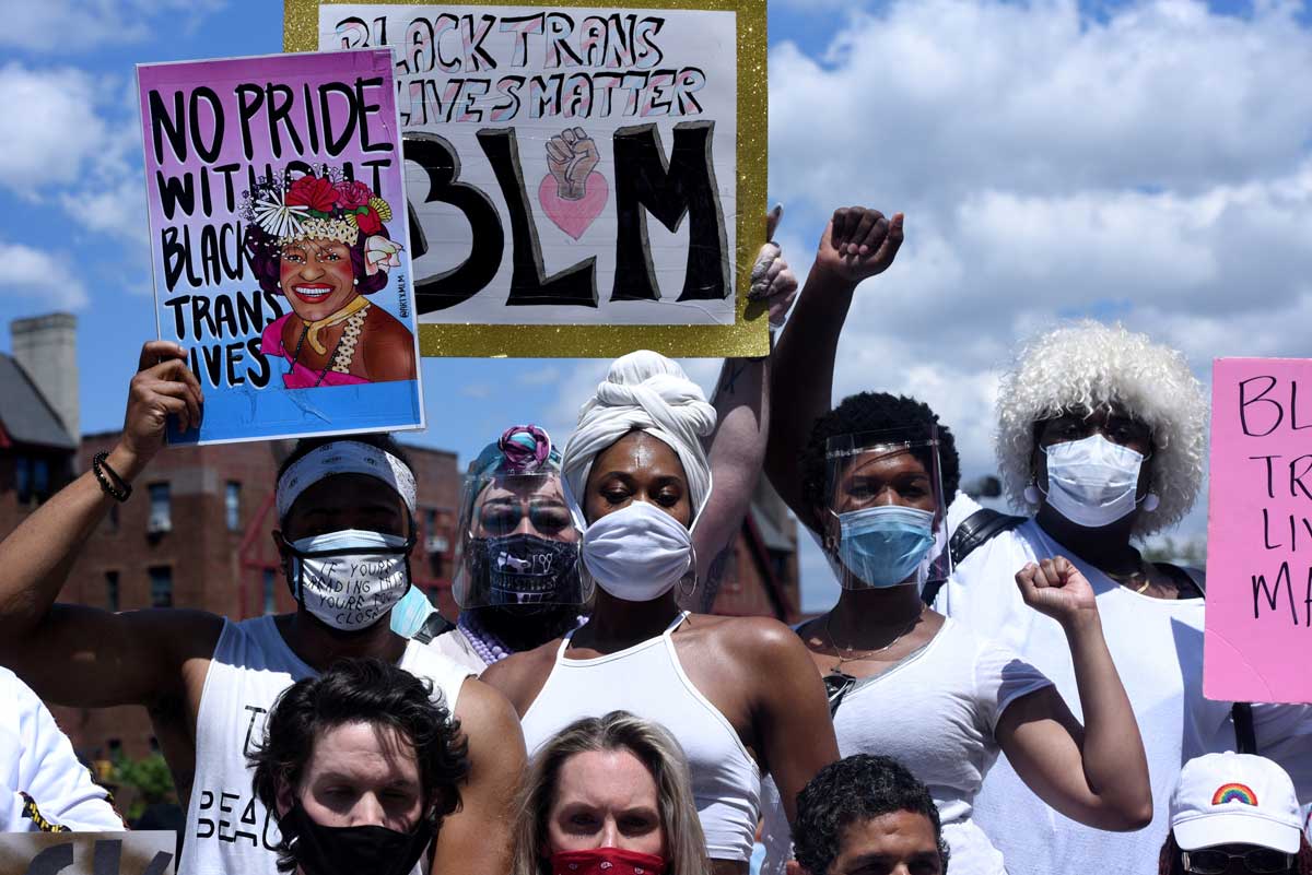 A gathering of five people wearing masks and holding signs that read "No pride without Black trans lives" REUTERS/Stephanie Keith