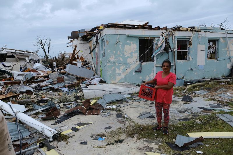 A woman poses for a photo near her damaged home in the aftermath of Hurricane Dorian