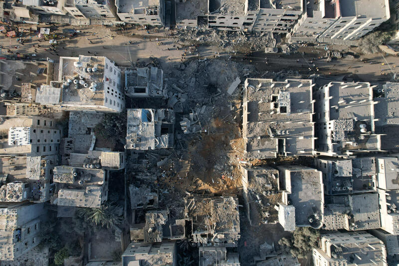 An overhead shot of people gathering around a crater in a residential area.
