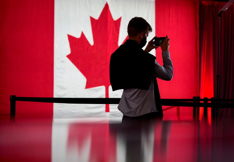 A person in front of a Canadian flag holds a cell phone ahead of the Liberal election night party, in Montreal, Quebec, Canada, September 20, 2021. REUTERS/Carlos Osorio