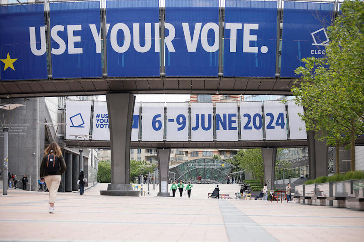People walk near signs for the upcoming European elections, at the EU Parliament in Brussels, Belgium May 23, 2024. REUTERS/Johanna Geron