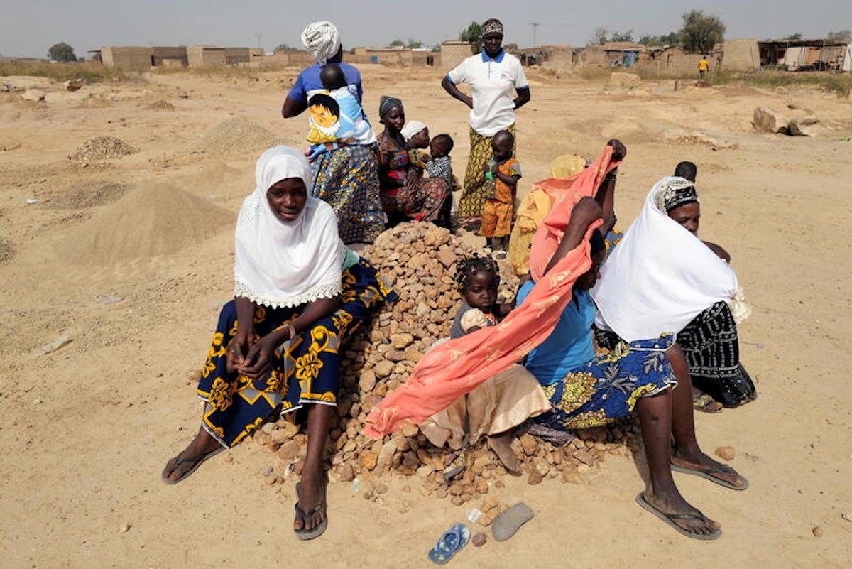 Women and their children who fled from attacks of armed militants in Soum province of Sahel Region, sit on a pile of rocks that they will turn into powder for sale to construction workers, at an informal camp for displaced people on outskirts of Ouagadougou, Burkina Faso November 19, 2020. Picture taken November 19, 2020. REUTERS/Zohra Bensemra