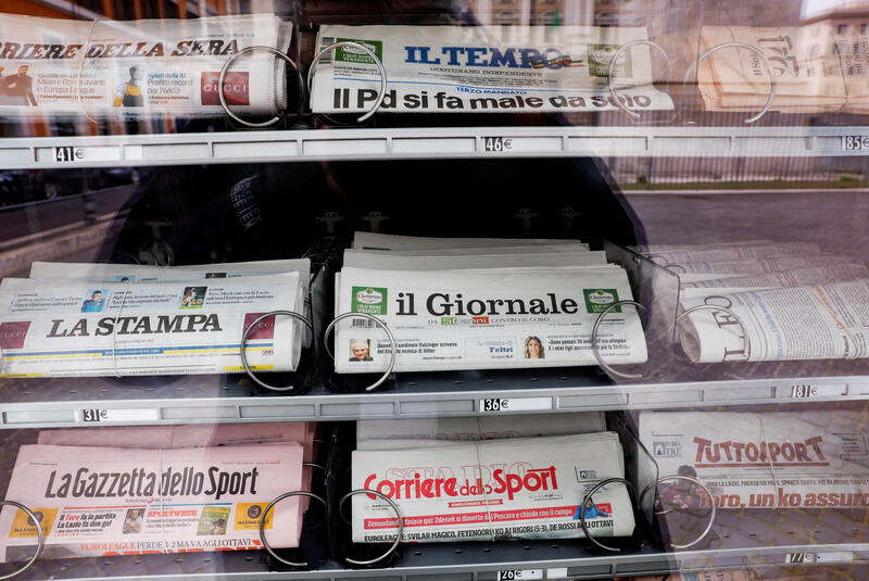 An Italian newspaper vending machine stands inside a kiosk.