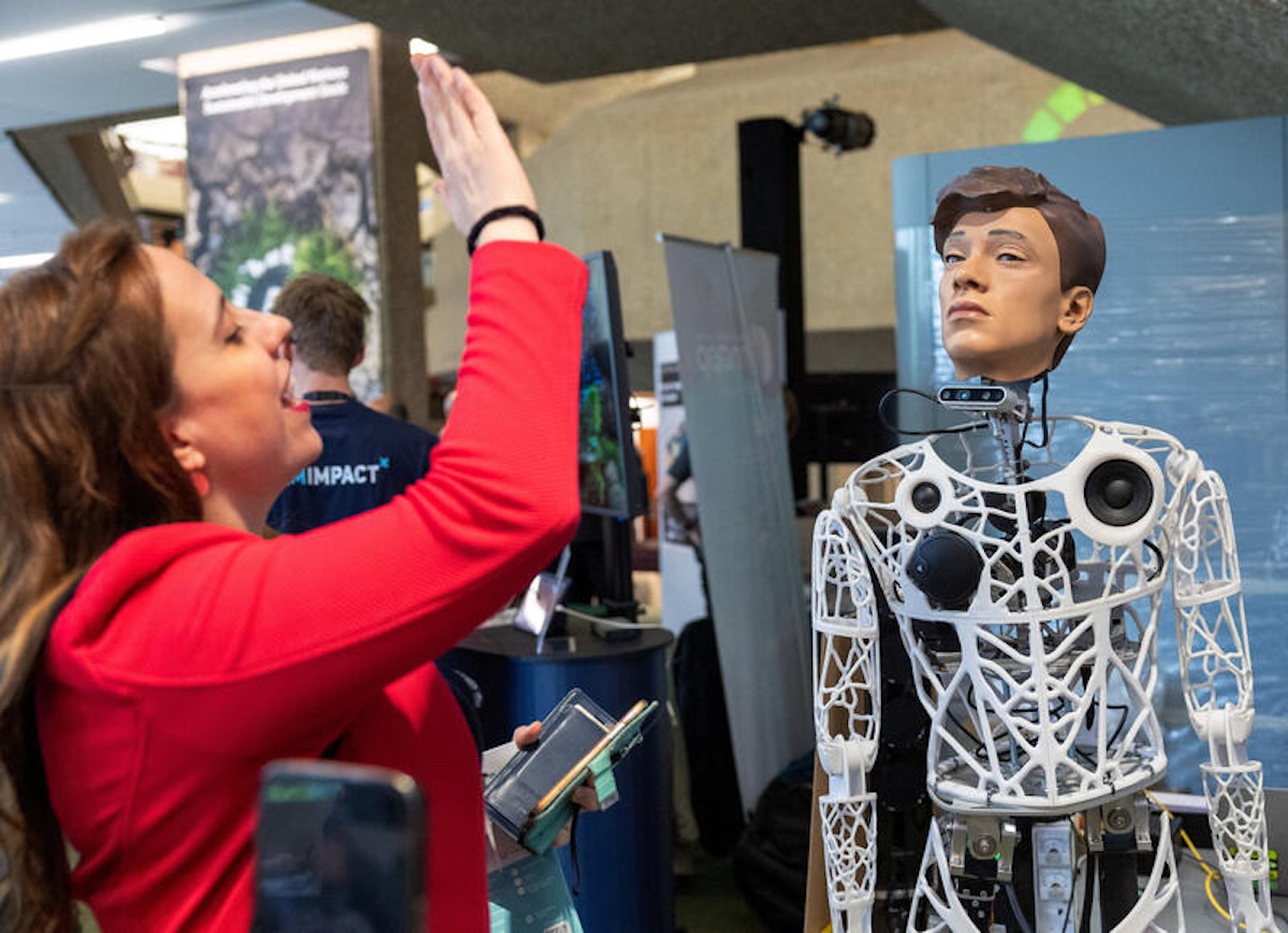 Ana Cristina García waves to Captcha, a robot by Hidoba Research, during the AI for Good Global summit in Geneva. REUTERS/Denis Balibouse