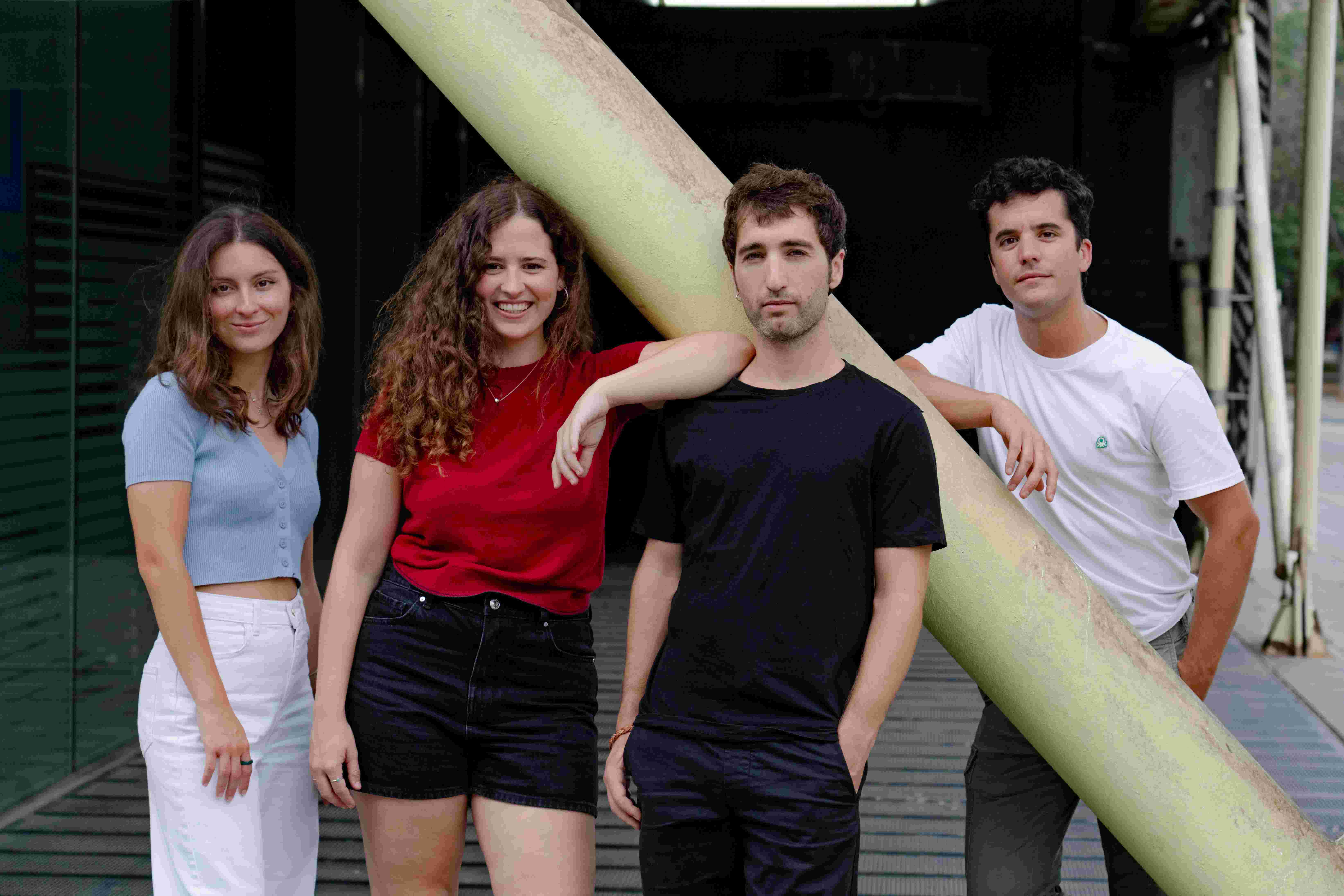 Four young people pose smiling in front of a building.