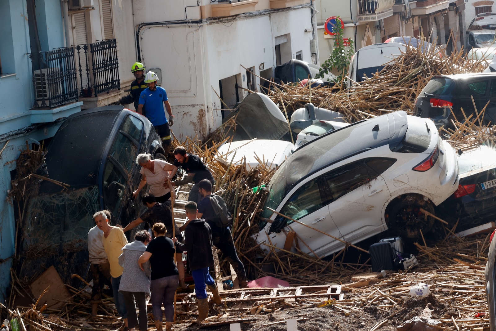 People work on a mud-covered street with damaged cars in the aftermath of torrential rains that caused flooding, in Paiporta, Spain, October 31. REUTERS/Eva Manez