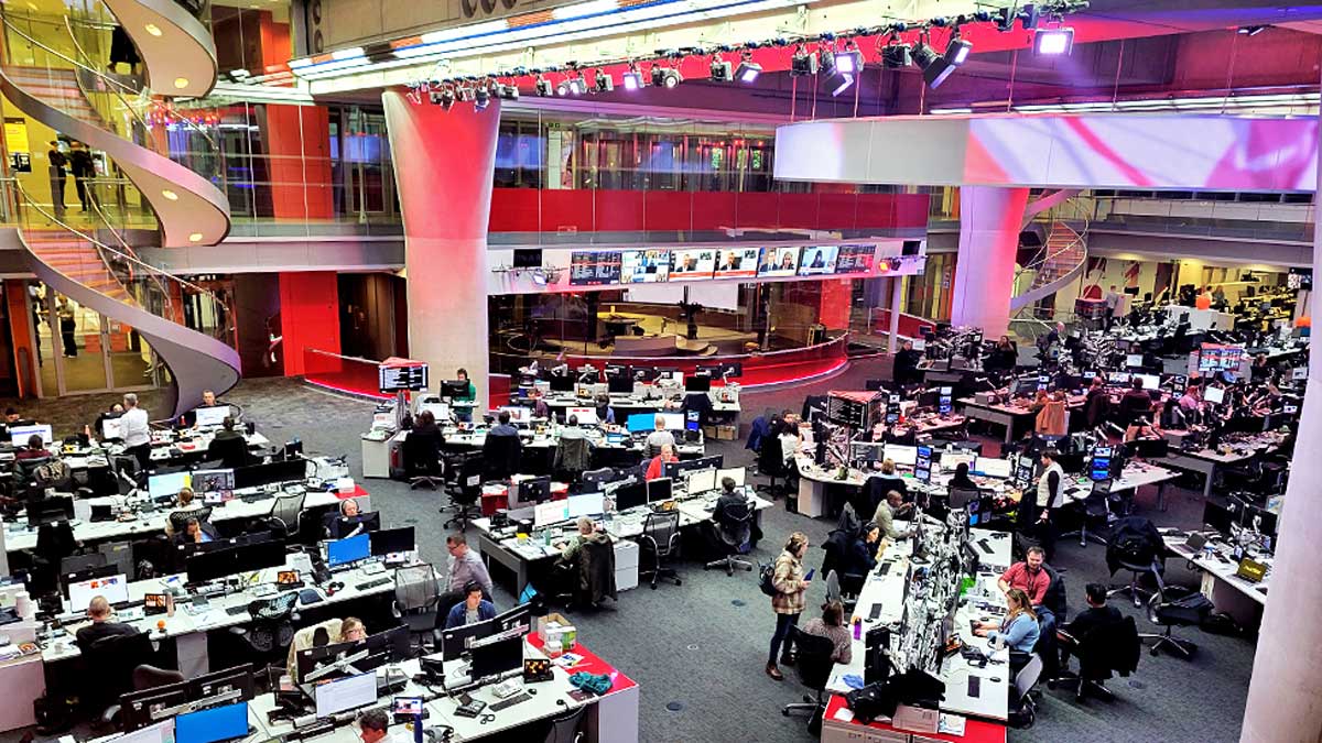 A birds-eye view of the BBC newsroom, showing desks in a well with a spiral staircase