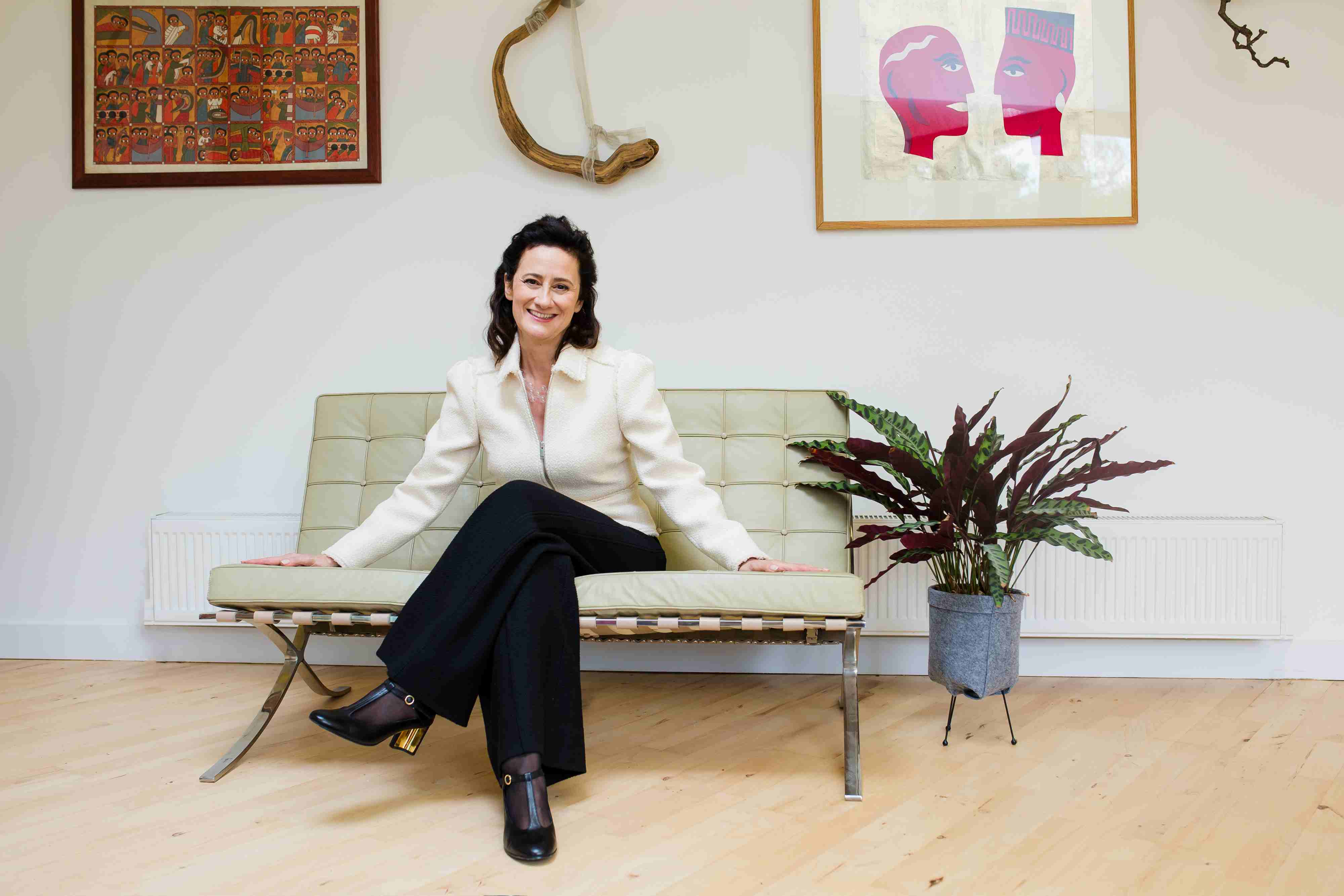 Emily Kasriel sits on a small sofa in what appears to be a living room.