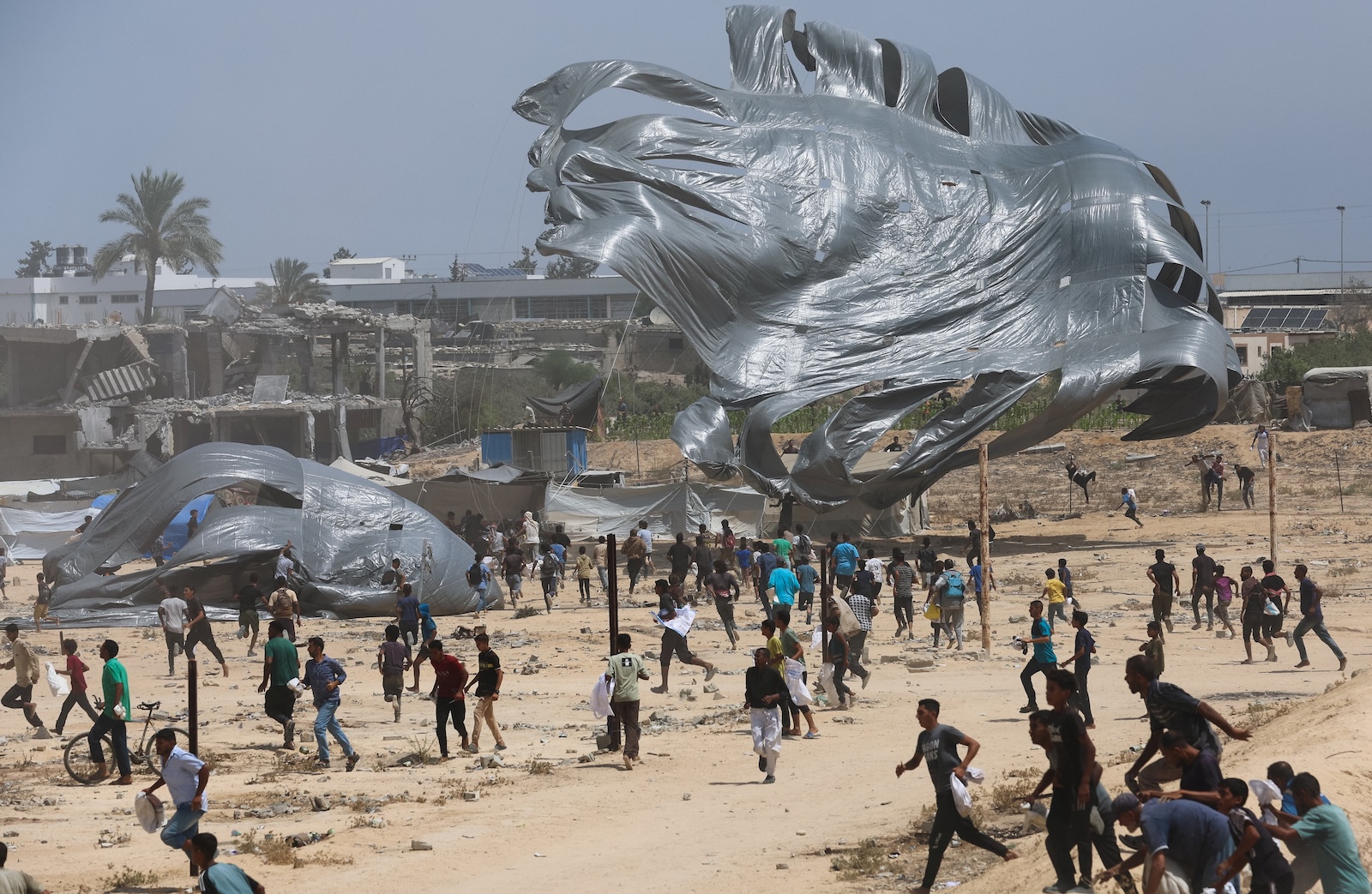Palestinians run towards airdropped aid packages, in Deir Al-Balah, in the central Gaza Strip August 19, 2025. REUTERS/Ramadan Abed