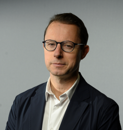 A headshot of Phil Chetwynd, a middle-aged man wearing a suit and glasses.