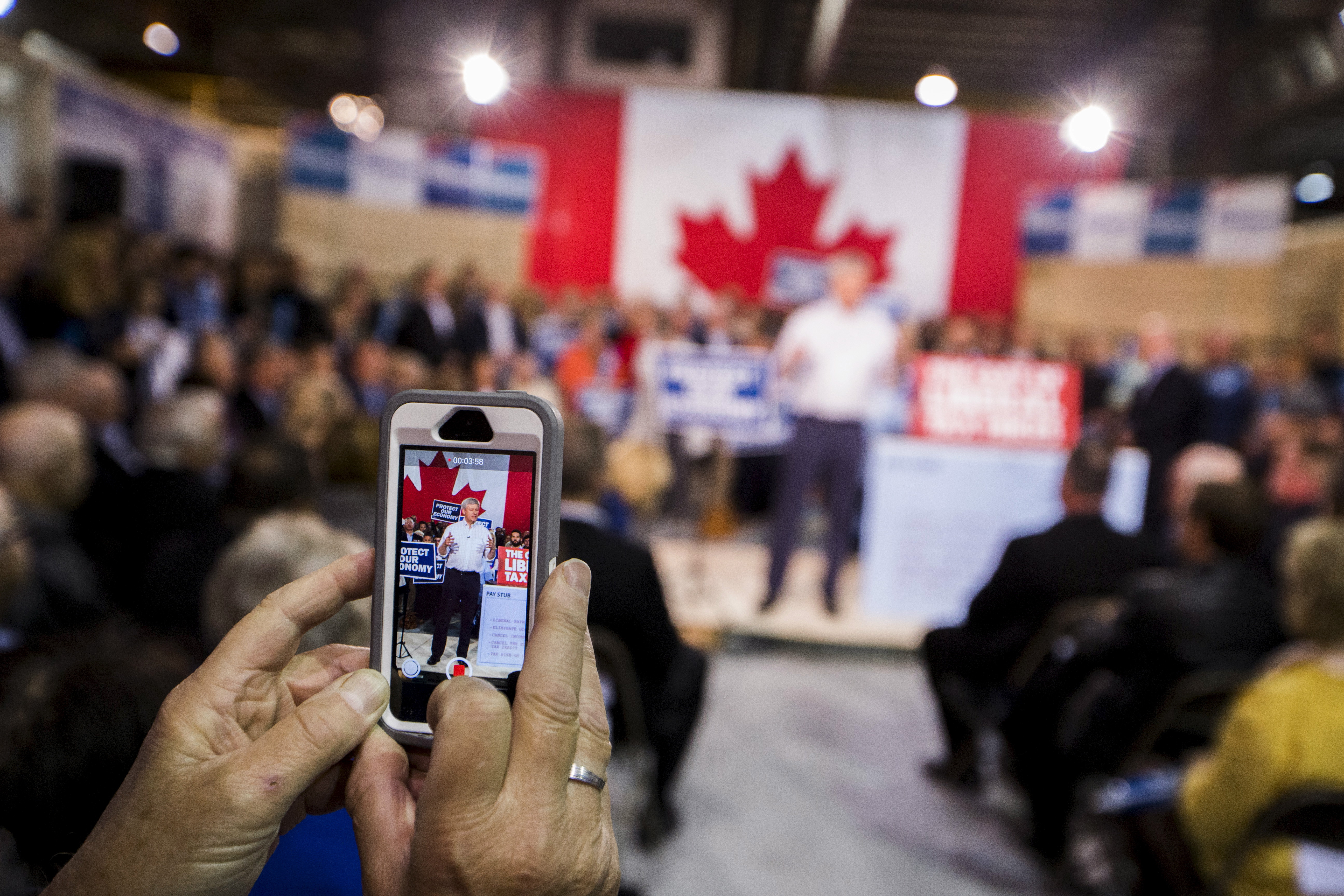 A man uses a smartphone to photograph Canada's Prime Minister and Conservative leader Stephen Harper at a rally in Fredericton, New Brunswick, October 16, 2015. Canadians will go to the polls for a federal election on October 19. REUTERS/Mark Blinch