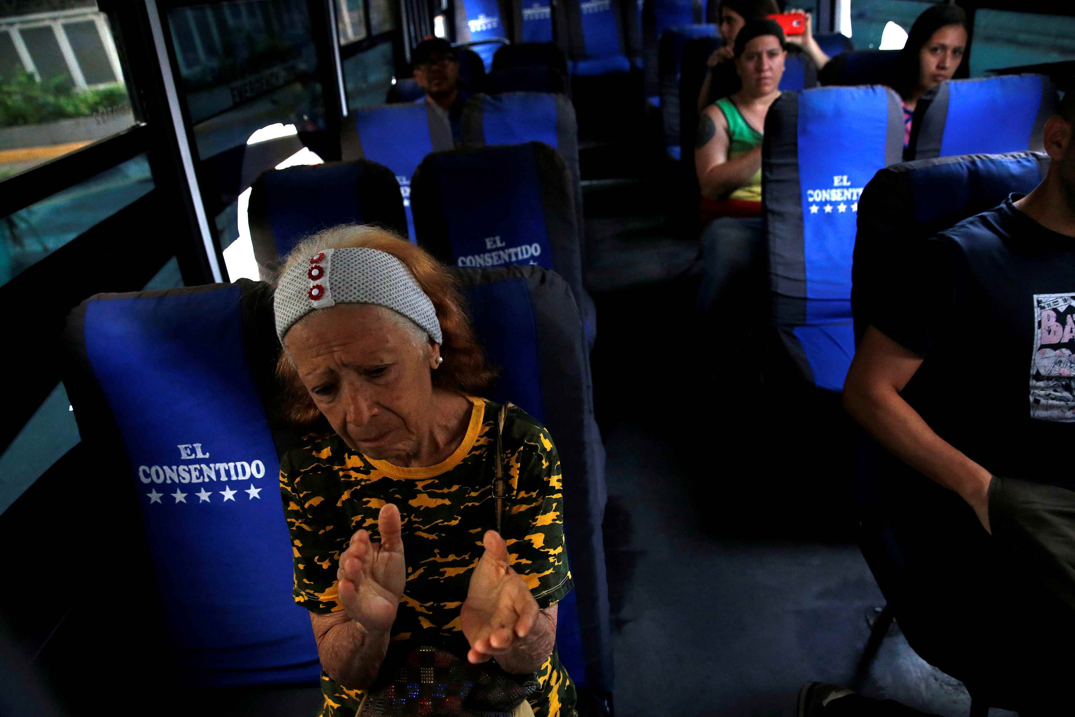 A woman seated in a bus applauds.