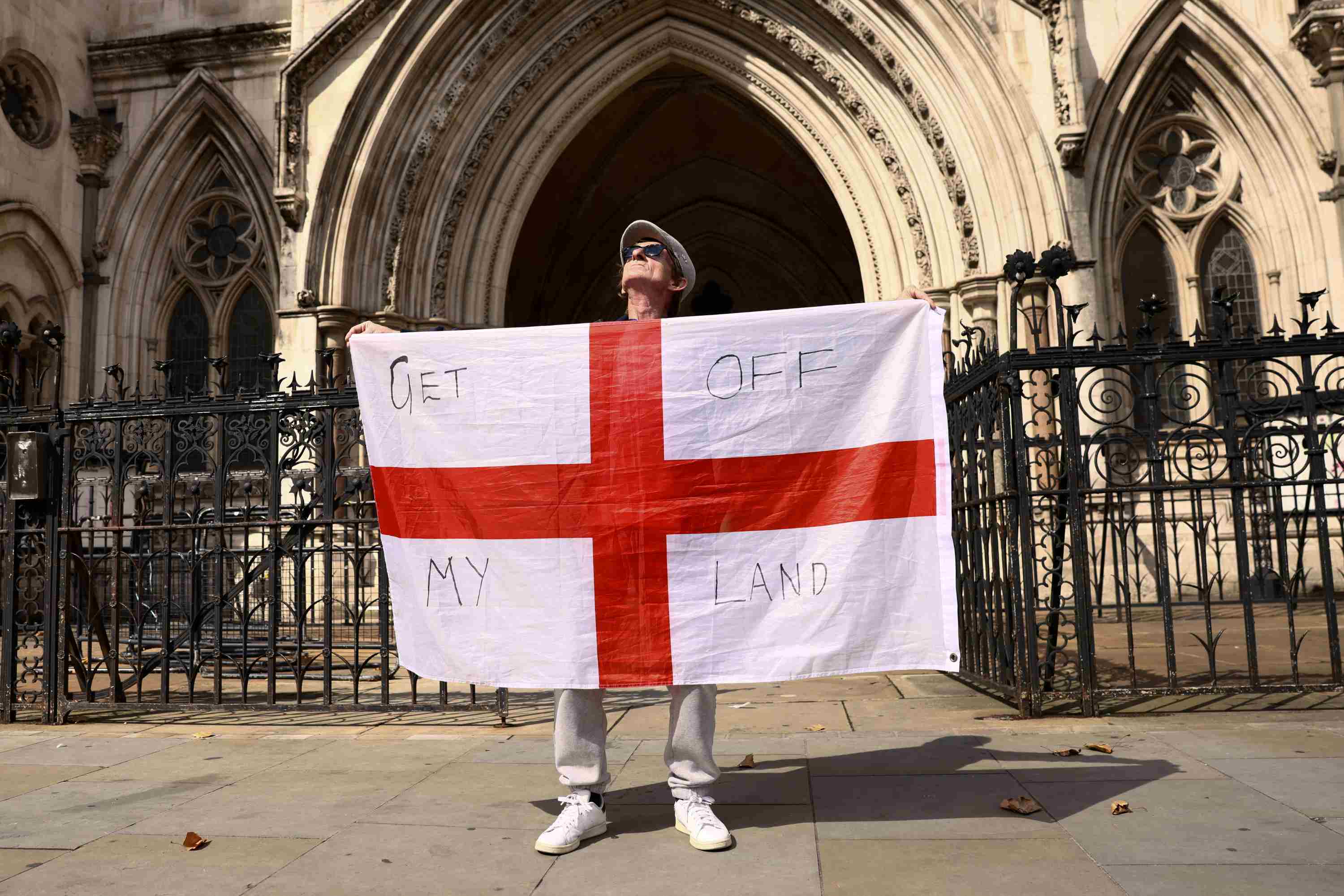 A protester holds up England's St George's flag outside the Royal Courts of Justice in London.
