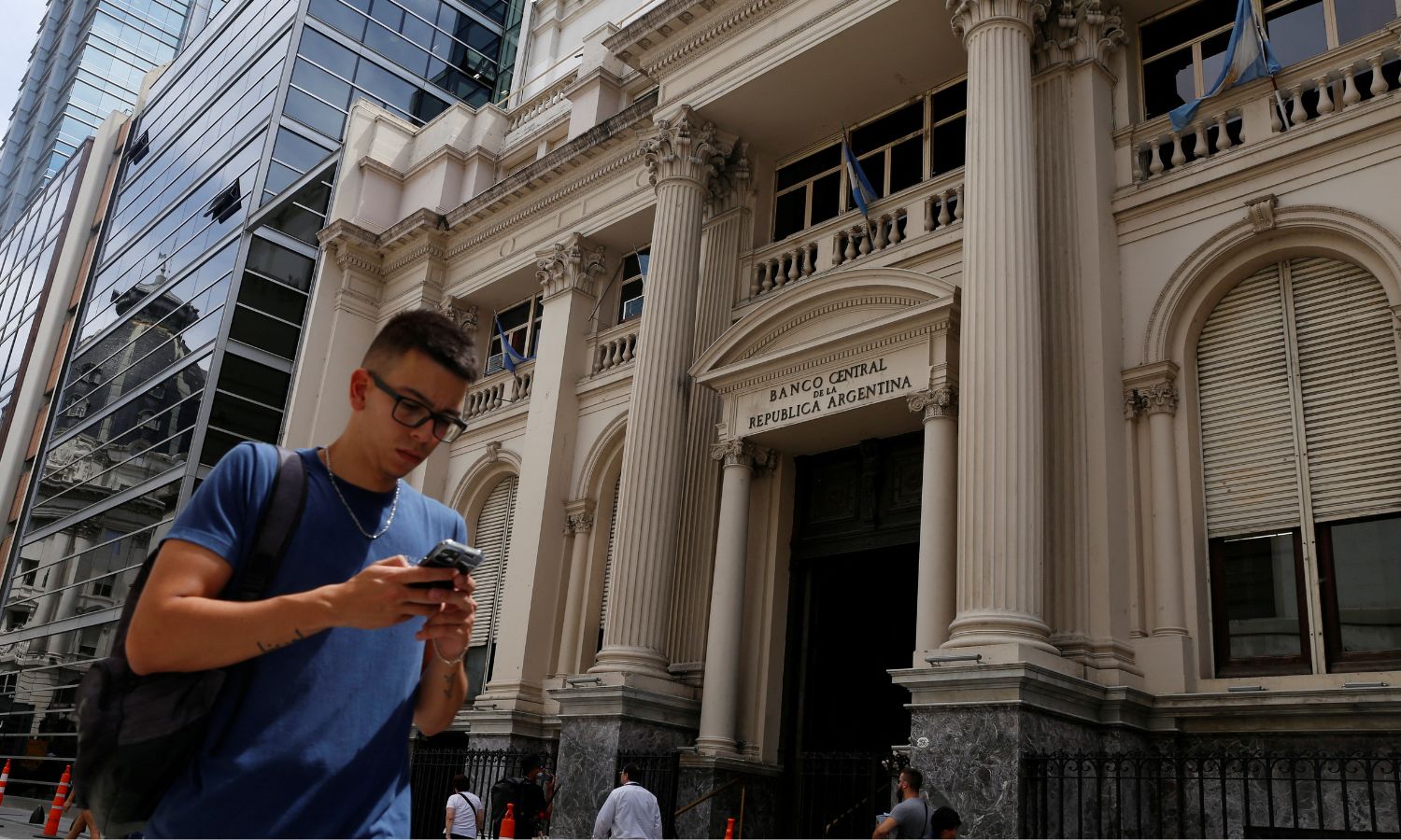 A man looks at his phone as he walks past Argentina's Central Bank in Buenos Aires