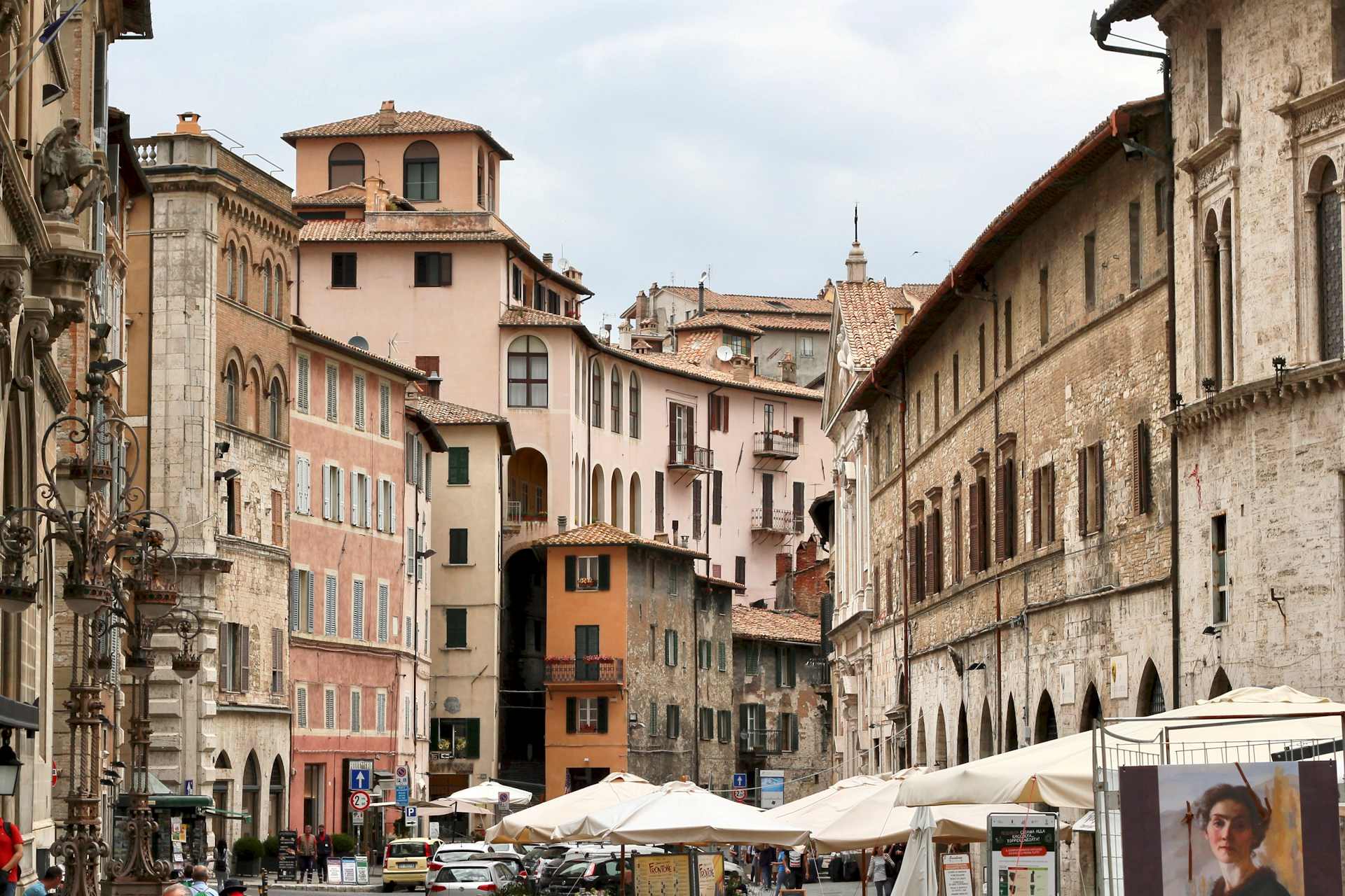 A street view of a jumble of medieval and renaissance brick and stucco buildings.