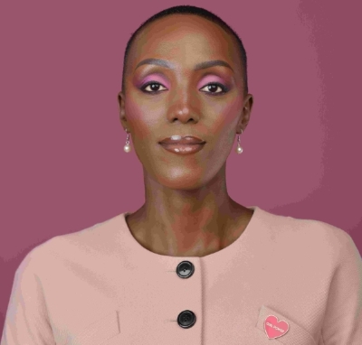 A professional photograph of a woman in a pink jacket with a badge reading "Girl Power"