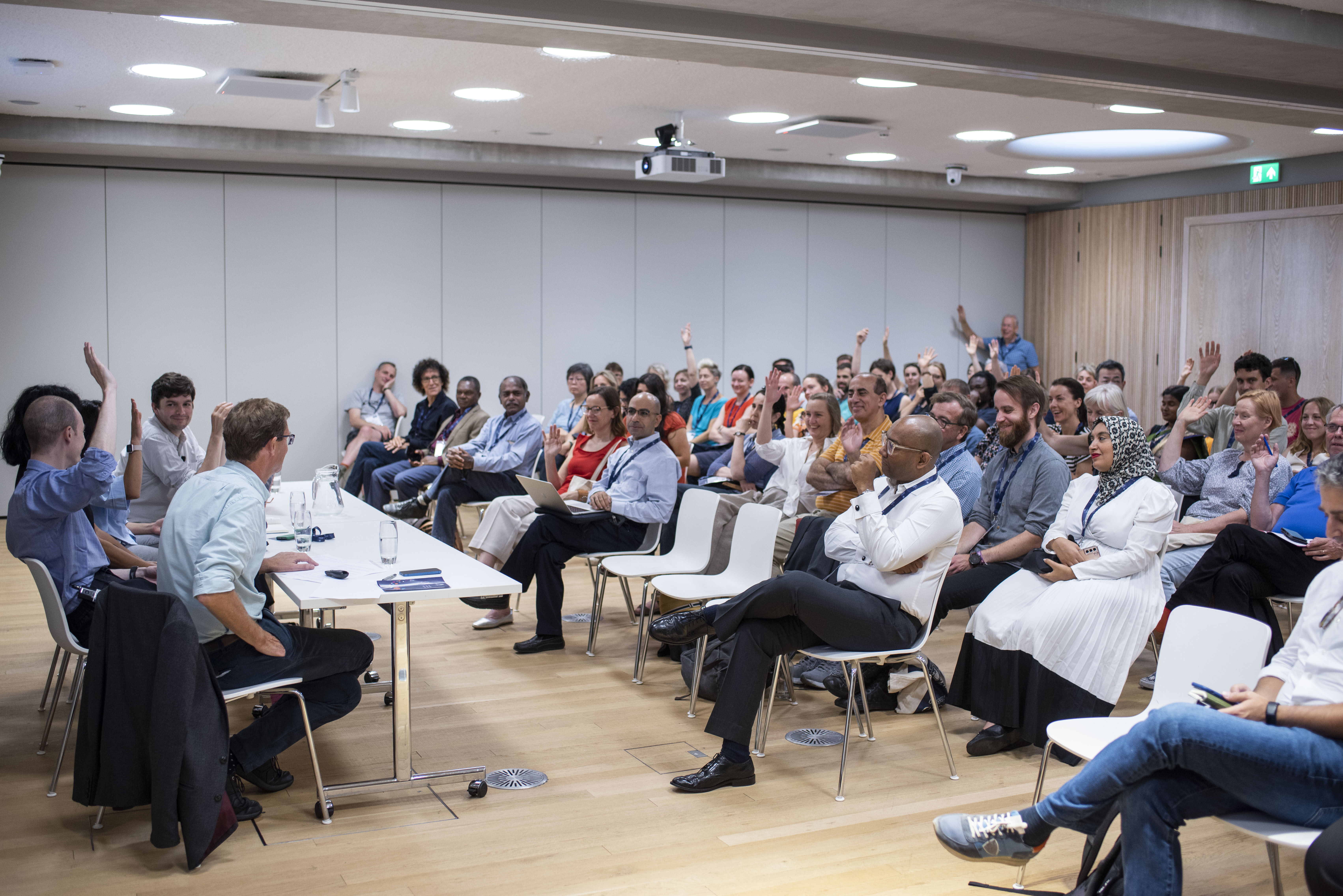 The audience of a panel session raises their hands during a Q/A.