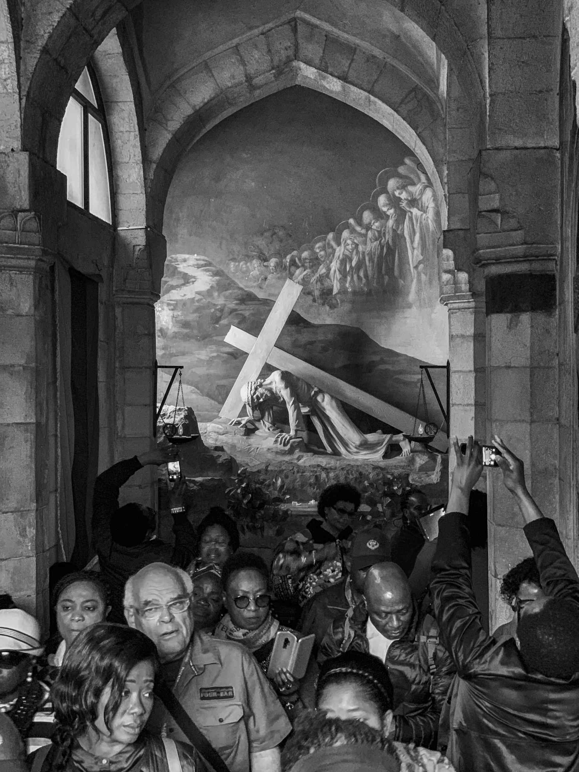 A black and white photo of a group of people crowding inside a chapel.