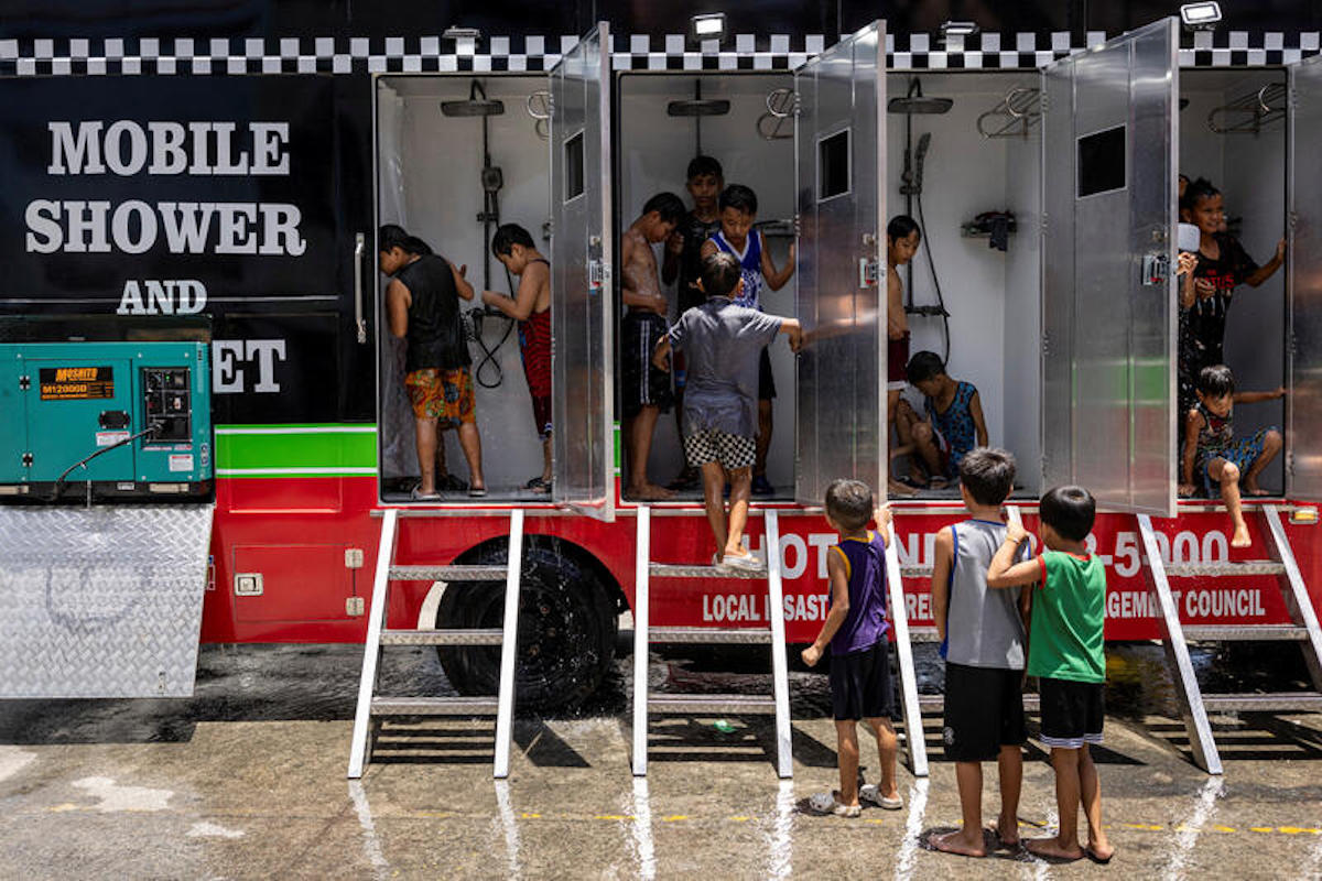 Children use a mobile shower provided by the local government, amid extreme heat in Valenzuela, Metro Manila, Philippines in May 2024. REUTERS/Eloísa López