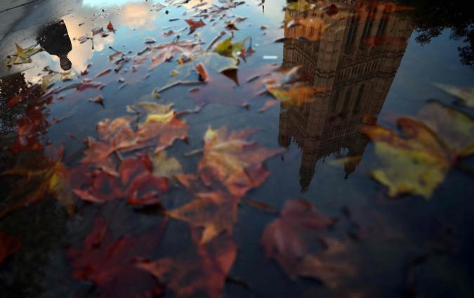 A man walking past the Houses of Parliament is reflected in a puddle. REUTERS / Hannah McKay