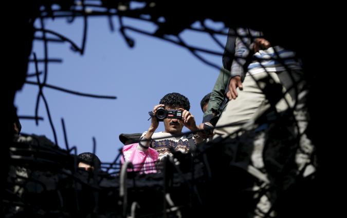 A journalist films the site of a Saudi-led air strike on a bridge in Yemen's capital Sanaa March 23, 2016. REUTERS/Khaled Abdullah