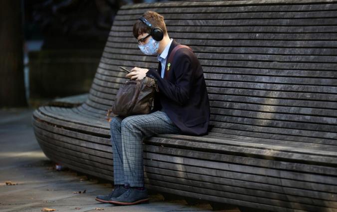 A person wearing a protective mask looks at a mobile phone in Manchester. 