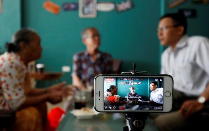 Rights activist Le Van Dung (R) live streams on Facebook in a coffee shop in Hanoi, Vietnam May 15, 2018. Picture taken May 15, 2018. REUTERS/Kham