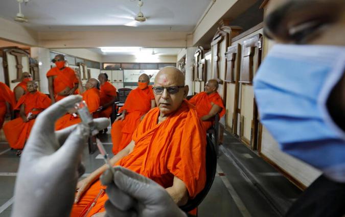 A Hindu saint watches a healthcare worker fill a syringe with COVISHIELD, a coronavirus disease (COVID-19) vaccine manufactured by Serum Institute of India, before injecting it to him, inside a temple premises in Ahmedabad, India, March 8, 2021. REUTERS/Amit Dave