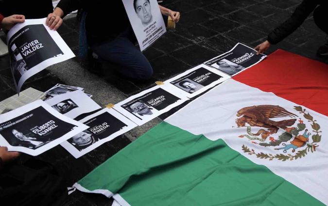 People place photos of murdered journalists next to the national Mexican flag in Buenos Aires. Reuters/Marcos Brindicci